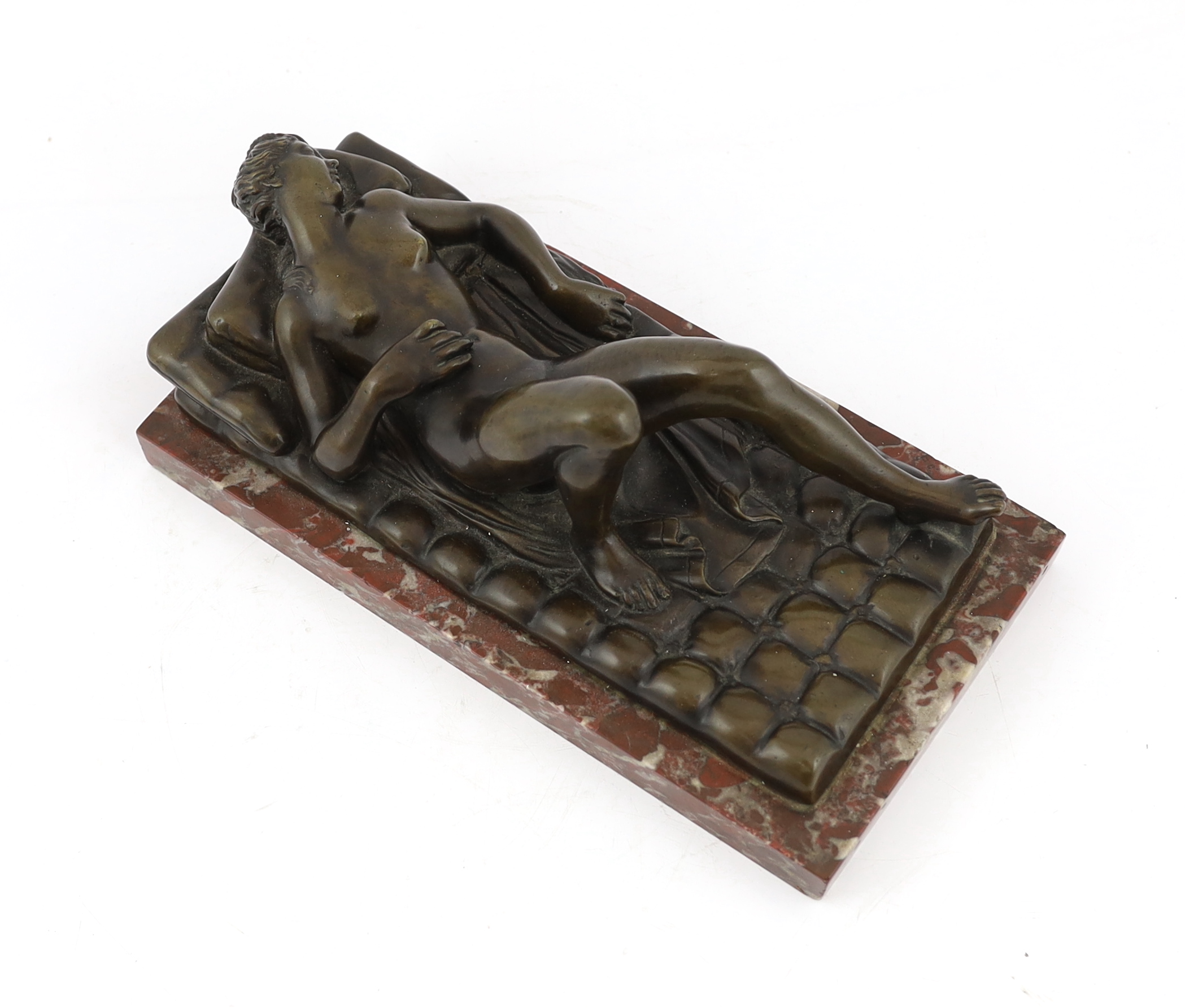 A late 19th/early 20th century bronze female nude reclining on a bed, on a red marble base, 32cm long